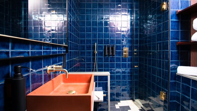 The shower room has dark blue tiles, and ochre-painted concrete wash-basins.