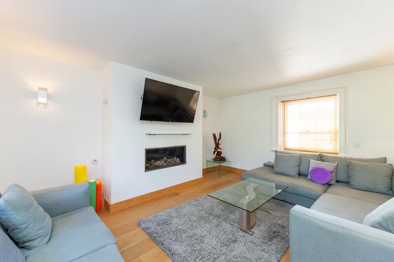 The living Room is dual-aspect with solid-wood flooring in oak and a gas inset stove.