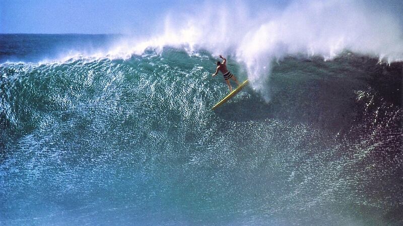 Greg Noll in 1963 at Waimea Bay, on the north shore of Oahu, in Hawaii. He first tempted fate there in 1957. Photograph provided by Bruce Brown and the Surfing Walk of Fame via The New York Times
