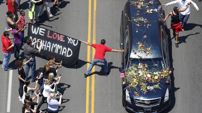A well-wisher holding a banner touches the hearse carrying the remains of Muhammad Ali during the funeral procession for the three-time heavyweight boxing champion in Louisville, Kentucky in June.  Photograph:  Reuters