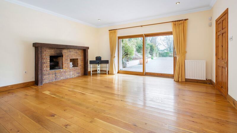 Oak-floored reception room with a large brick fireplace and patio doors opening into the garden.
