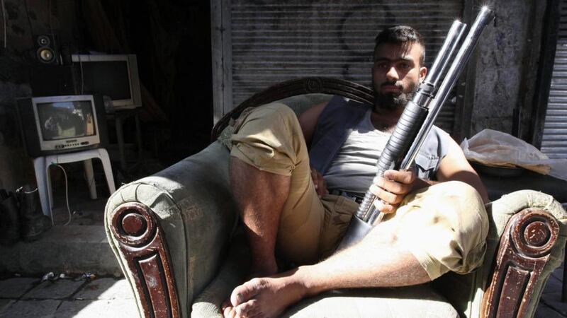 A Free Syrian Army member sits on a sofa with his weapon in the city of Aleppo yesterday. Photograph: Muzaffar Salman/Reuters