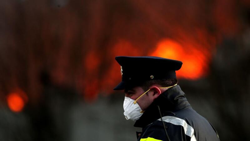 A garda wears a mask at the scene of a fire at the Oxigen plant in the Ballymount Industrial Estate. Up to 30 firefighters remain at the scene and are now ‘smothering’ what remains of the fire. Photograph: Brian Lawless/PA Wire