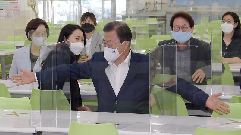 South Korean president Moon Jae-in (C) spreads his arms to measure the distance between seats at the cafeteria during a visit to a classroom at Jungkyung High School in Seoul on Friday. Photograph: Yonhap/EPA