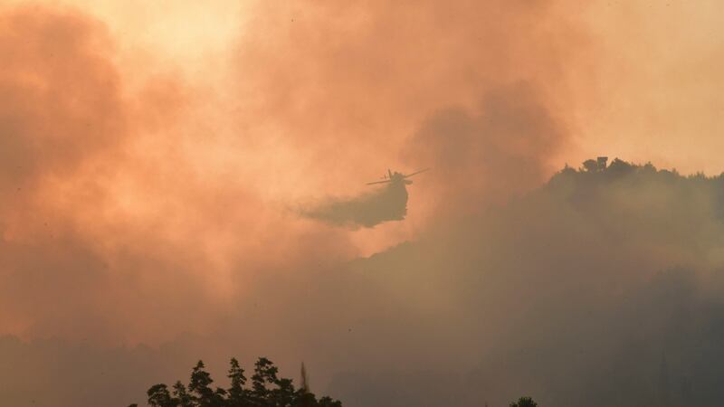 An aircraft drops water during a wildfire in ancient Olympia, western Greece. ‘Our forces fought an all-night battle . . . to keep the archaeological site and the town intact.’ Photograph: Giannis Spyrounis/ilialive.gr via AP