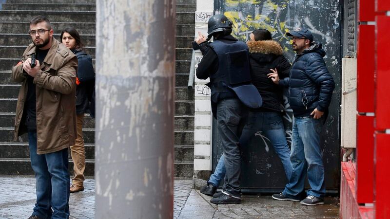 French police check a pedestrian as they secure the area after a man was shot  at a police station in the 18th district in Paris. Photograph: Philippe Wojazer/Reuters.