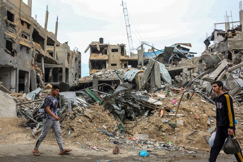 Palestinians pass the rubble of destroyed homes in the town of Al-Maghazi, in the central Gaza Strip, on Saturday. Photograph: Samar Abu Elouf/New York Times
                      