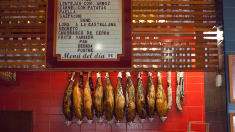 Legs of cured ham hang on the walls of the bar at Las Columnas in Seville. Photograph:  James Rajotte/The New York Times