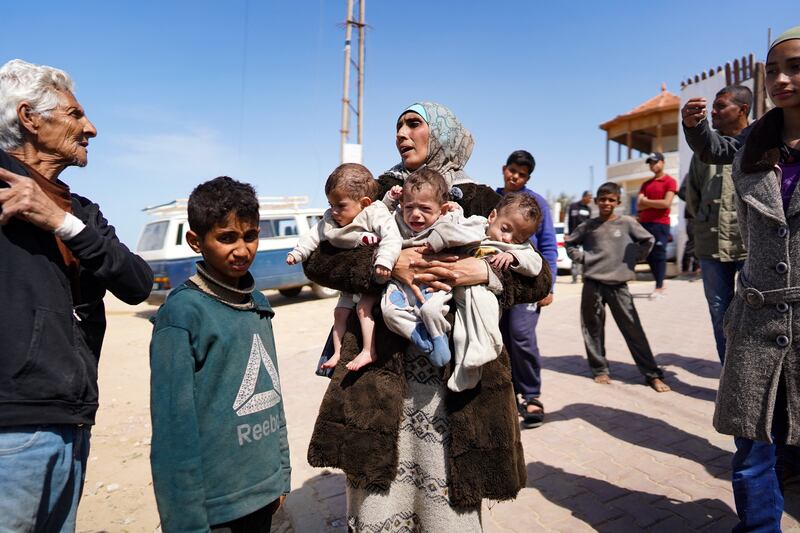 A woman carries three babies as she reaches the central part of the Gaza Strip after fleeing the Al-Shifa hospital compound in Gaza City. Photograph: AFP/Getty Images
