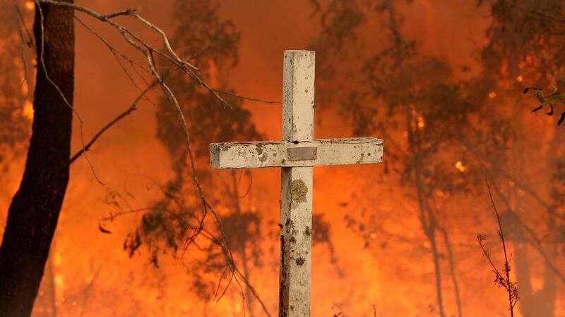 A bushfire burns behind a cross at Possum brush, near Taree, New South Wales. Photograph: EPA/DARREN PATEMAN