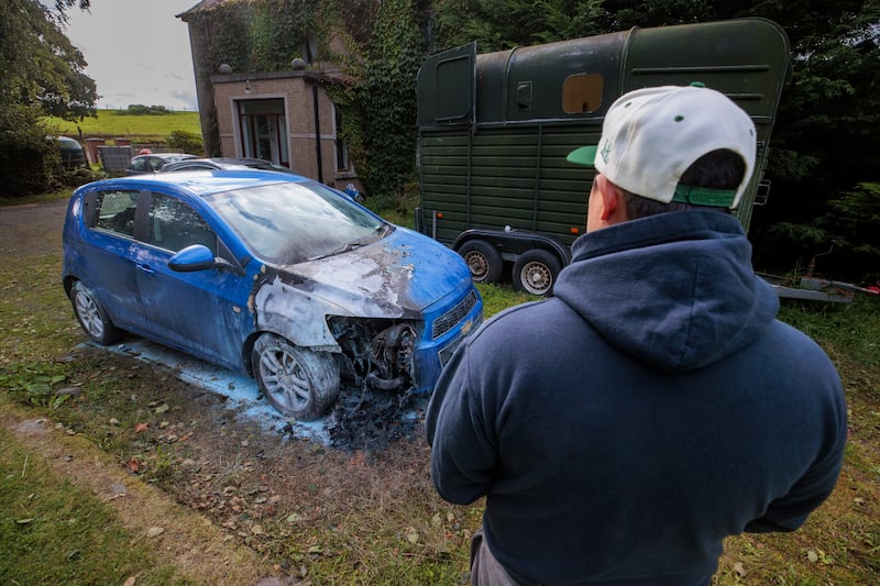 The owner of a vehicle looks on at its burnt remains after cars were set on fire in Ballymena, Co Antrim on Sunday in racist attacks. Photograph: Liam McBurney/PA Wire