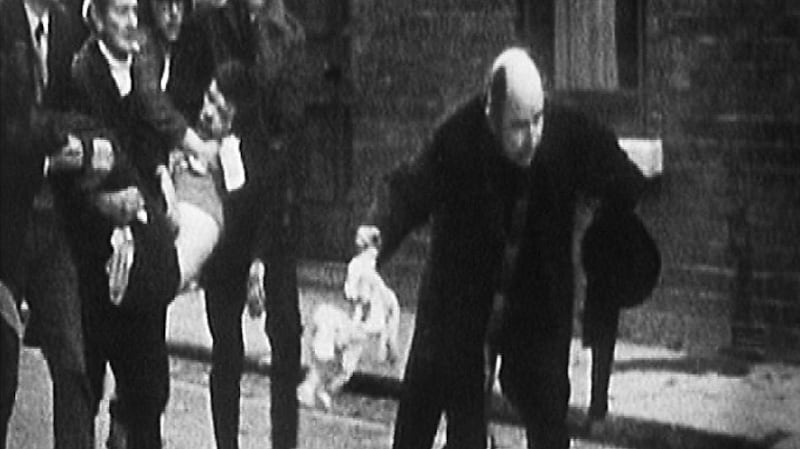 Powerful image: Bishop Daly was filmed waving a white handkerchief on Bloody Sunday, as attempts are made to carry Jackie Duddy to safety. Photograph: RTÉ Archives