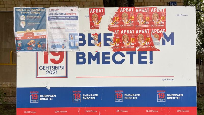 A Moscow sign saying ’Let’s choose together!’ ahead of Sunday’s Russian parliamentary elections, which has been covered over with posters for a Communist Party candidate and offers of prizes to people who register to vote online
