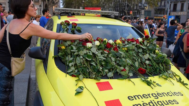 A woman places roses on  an  emergency services vehicle in Barcelona  during a march against terrorism, August 26th, 2017. Photograph: Lluis Gene/AFP/Getty Images
