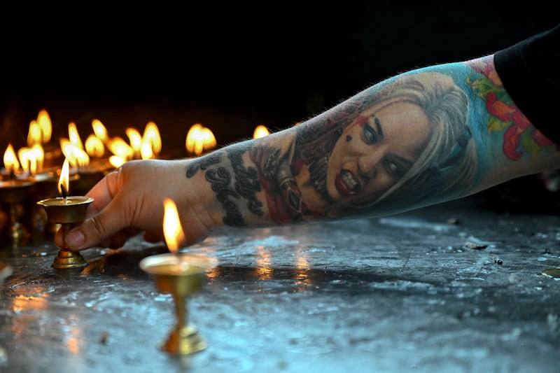 A woman lights an oil lamp inside a temple at the Durbar Square in Kathmandu. Photograph: Arun Sankar/ AFP via Getty Images       