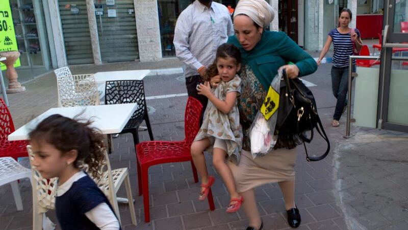 Members of an  Israeli family run towards a shelter among some shops in the southern Israeli town of Sderot yesterday as a siren sounds, signalling a rocket attack launched from the Gaza Strip. Photograph: Jim Hollander/EPA