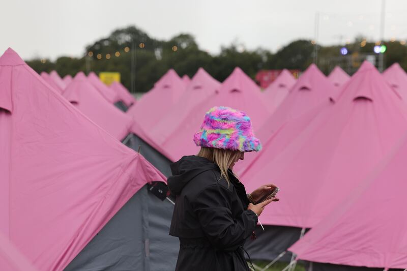 Electric Picnic 2025: A festivalgoer checks her phone amid a sea of pink tents all set up at the Silver campsite. Photograph: Alan Betson