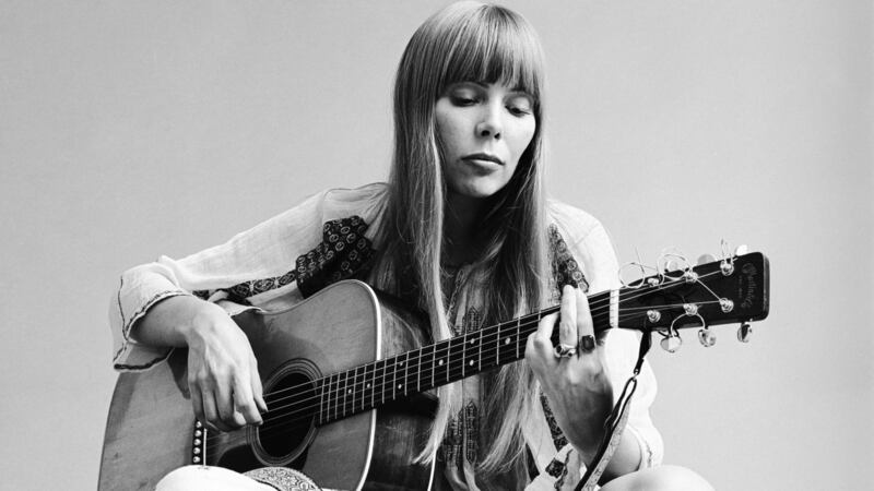 Portrait of Canadian musician Joni Mitchell seated on the floor playing acoustic guitar in November 1968. This image is from a shoot for the fashion magazine Vogue. Photograph: Jack Robinson/Getty Images
