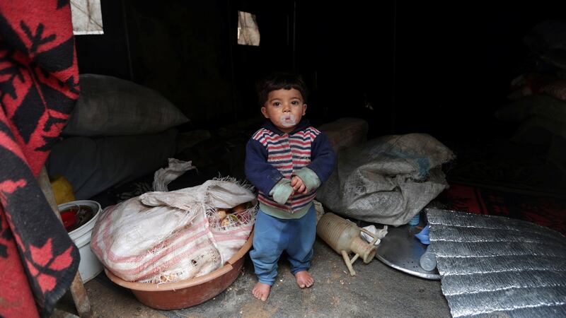 An internally displaced child looks out from a tent, erected at an empty school and university compound used as shelter in Azaz, Syria. Photograph: Khalil Ashawi/Reuters