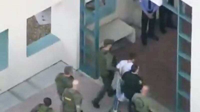 Police escort a suspect into the Broward Jail after checking him at the hospital following the shooting at Marjory Stoneman Douglas High School in Florida.  Photograph: Reuters