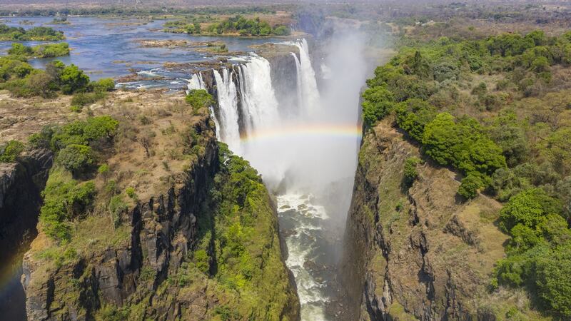 Aerial few of Victoria Falls with a large rainbow over the falls. This is right at the border between Zambia and Zimbabwe in southern Africa.