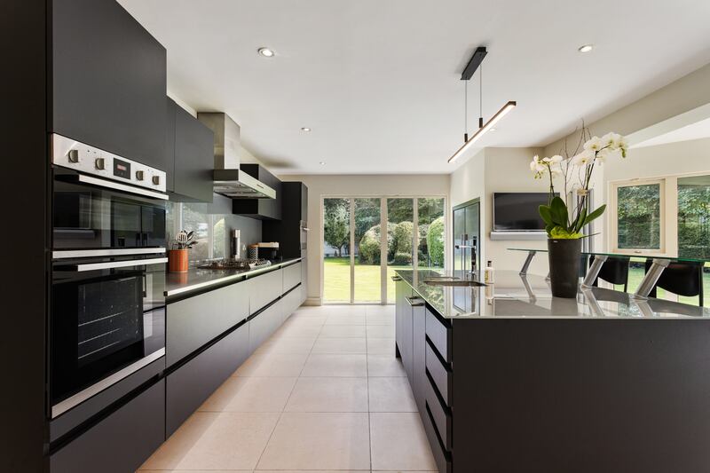 The kitchen features a central island, Neff double oven, Smeg gas hob and Gutman extractor hood. 