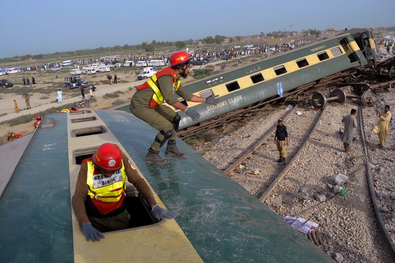 Rescue workers look for survivors at the site of the derailed train. Photograph: Umair Ali/AP