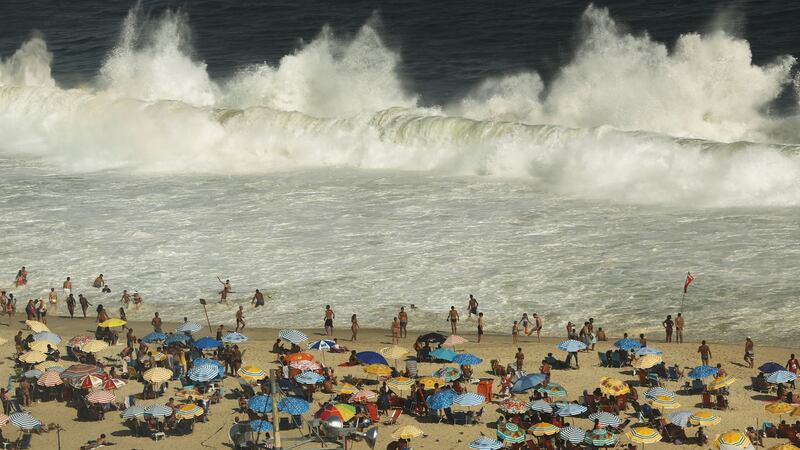 Waves break as people gather on Copacabana beach. Photograph: Mario Tama/Getty Images