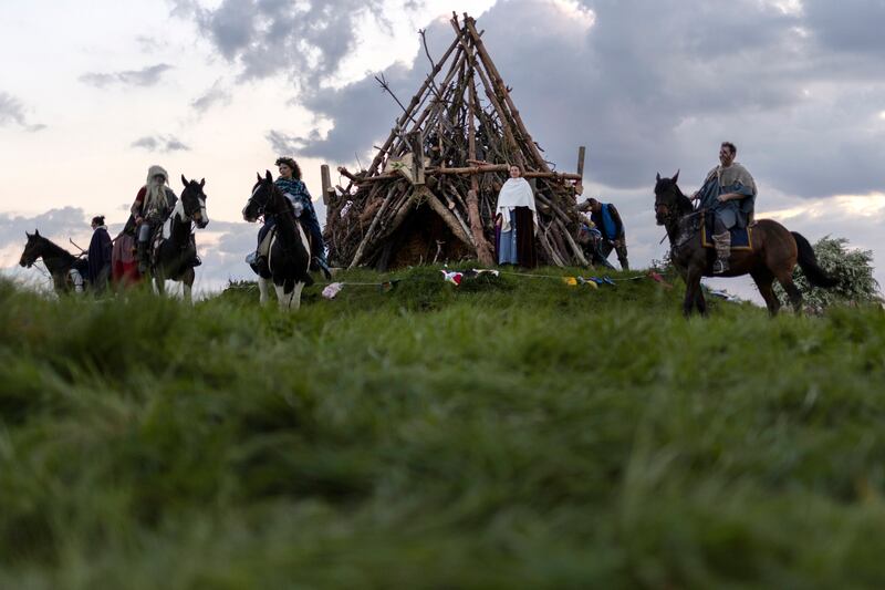 Horsemen circle the unlit bonfire pile