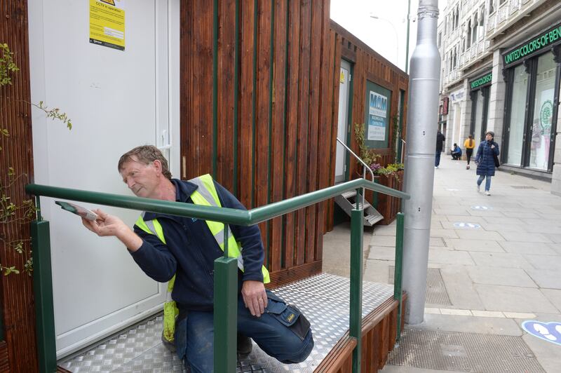A worker puts the finishing touches to the newly installed public toilets at the top of Grafton Street, at St Stephens Green, Dublin in 2021. Those toilets will remain open, the city council has said. Photograph: Dara Mac Dónaill