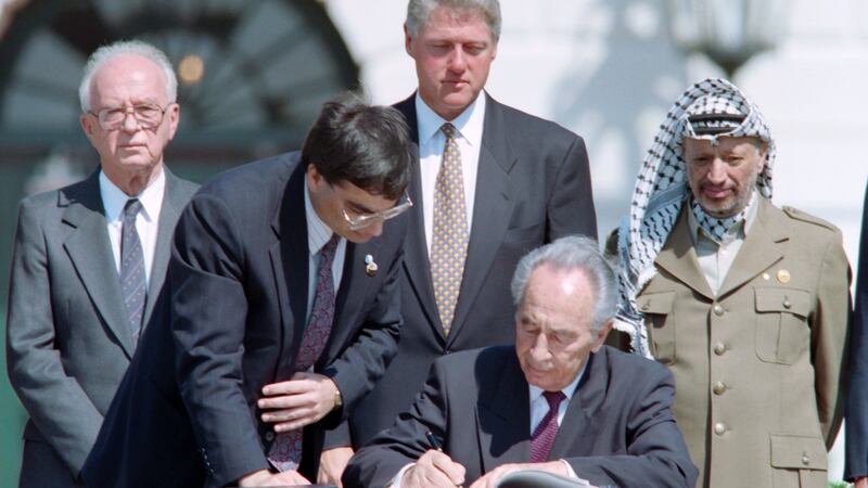 Shimon Peres signs the Oslo Accords as Bill Clinton and Yasser Arafat look on in September 1993. Photograph: David Ake/AFP/Getty Images