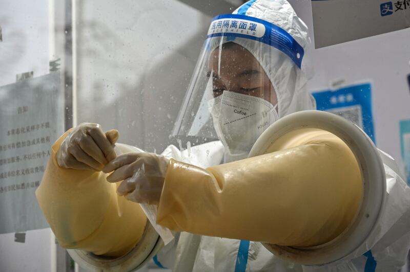 A health worker  prepares to take a swab sample from a person to test for the Covid-19 coronavirus in the Jing'an district in Shanghai on December 7, 2022. (Photo by Hector RETAMAL / AFP) (Photo by HECTOR RETAMAL/AFP via Getty Images)
