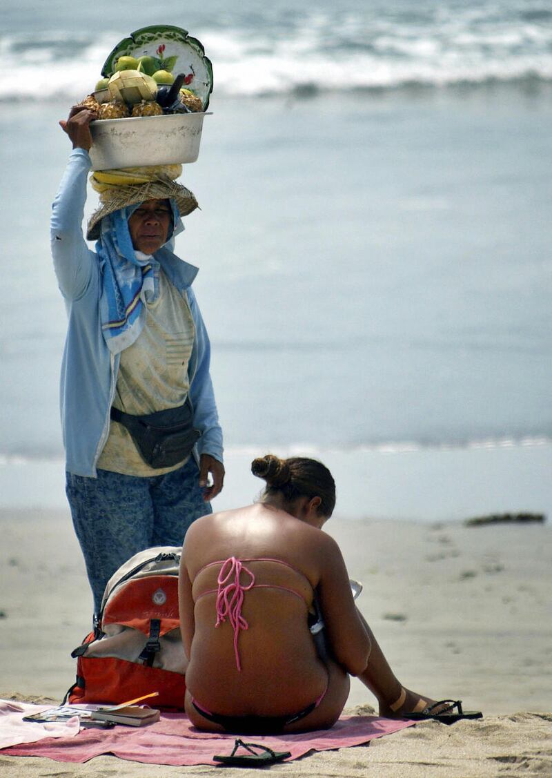 The photograph used on the cover of Lessenich’s book. A vendor walks past a foreign tourist enjoying the sun at Kuta beach, on Bali island in December 2006. File photograph: Sonny Tumbelaka/AFP Photo/Getty Images