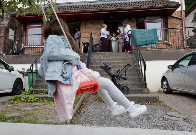 Lucan resident Antonia Popescu plays on a swing while her mother  and sister, Tatiana Popescu and Victoria, speak to Catherine Murphy (left) and Sinead Gibney of the Social Democrats while they were on the canvass in Lucan. Photograph: Alan Betson/The Irish Times

