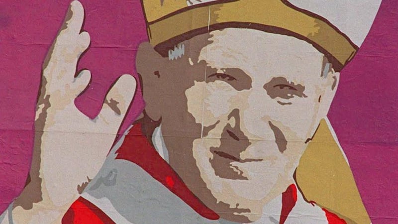 Cuban women sit in front of one of the numerous billboards throughout Havana welcoming Pope John Paul II to the island. Photograph: AP Photo/Gregory Bull