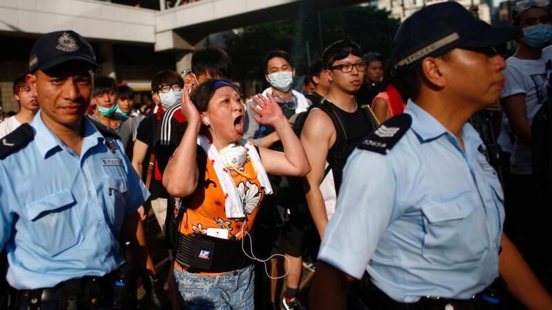 A woman shouts to a police officer as demonstrators block the main street to the financial Central district, outside the government headquarters in Hong Kong today. Photograph: Reuters
