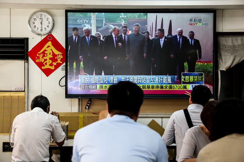 A TV shows Chinese president Xi Jinping flanked by Vladimir Putin and Kim Jong-un during the military parade in Beijing on Wednesday. Photograph: I-Hwa Cheng/AFP via Getty Images