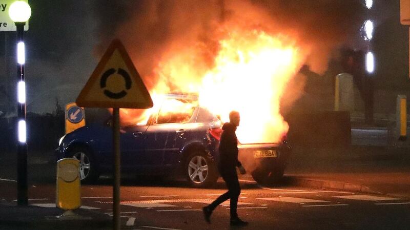A man walks past a burning car hijacked by loyalists at the Cloughfern roundabout in Newtownabbey, Co Antrim. Photograph: Peter Morrison/PA Wire