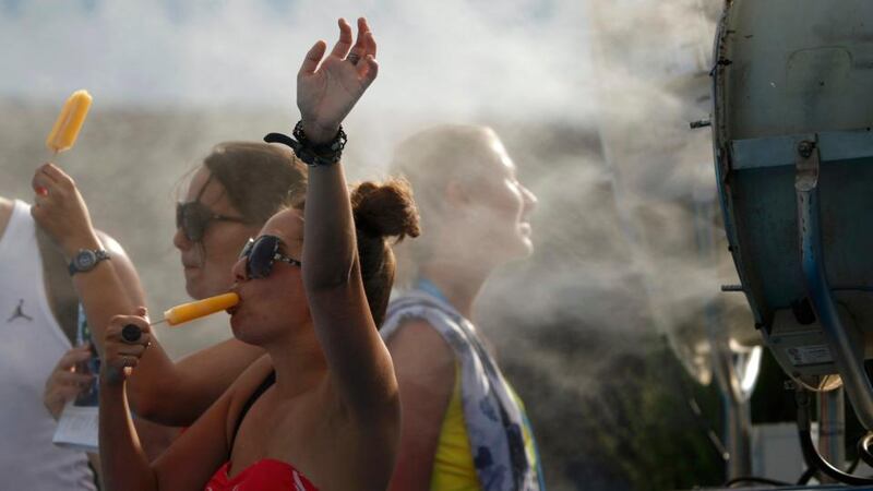 Spectators cool off with ice pops  in front of a misting fan at the Australian Open  in Melbourne, where temperatures were again over 40 degrees Celsius. Photograph:  Jason Reed. Photograph: Reuters