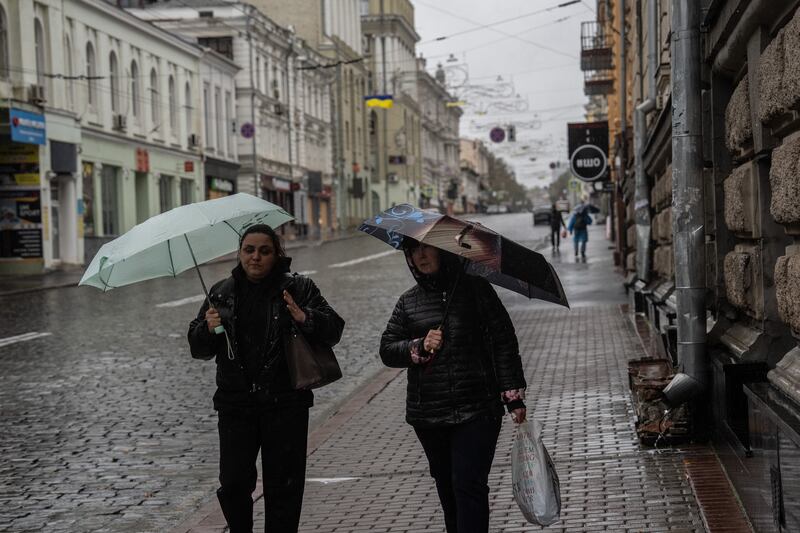 Women shelter under umbrellas as they walk along a street after a Russian attack on a power station caused power cuts across Kharkiv in October. Photograph: Carl Court/Getty Images