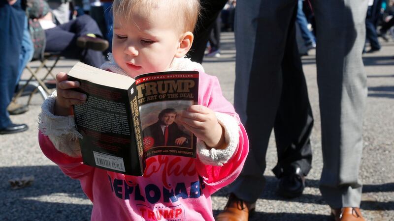 Grace Mahoney, 16 months, looks at a copy of The Art of the Deal before  a Donald Trump rally  in Portsmouth, New Hampshire last year. Photograph: Mary Schwalm/AFP/Getty Images
