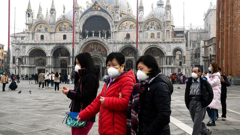 Tourists wearing protective facemasks visit the Piazza San Marco, in Venice, on Monday during the usual period of the Carnival festivities which the last two days have been cancelled due to an outbreak of the COVID-19. Photograph:   (Andrea Pattaro/AFP via Getty Images)