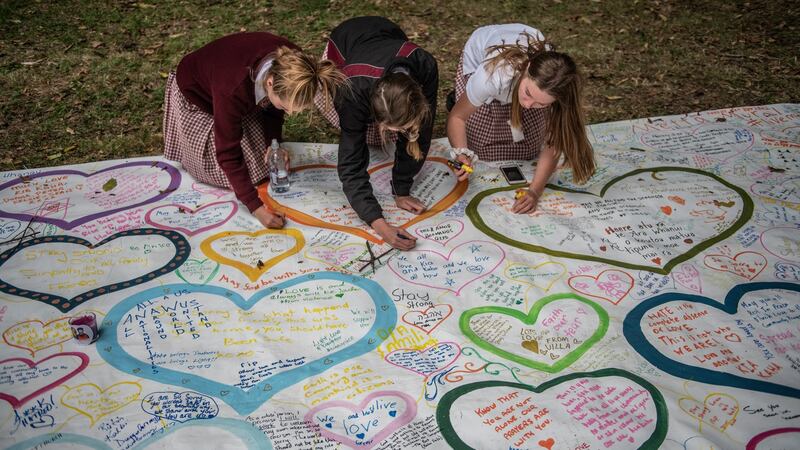 Schoolgirls write messages on a banner during a students vigil near Al Noor mosque on March 18th. Photograph:  Carl Court/Getty Images