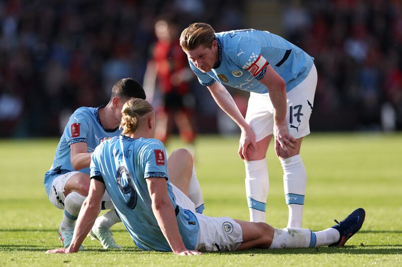 Manchester City team-mates Kevin De Bruyne (right) and Phil Foden check on Erling Haaland after sustaining an injury during the FA Cup quater-final against Bournemouth. Photograph: Alex Pantling/Getty Images