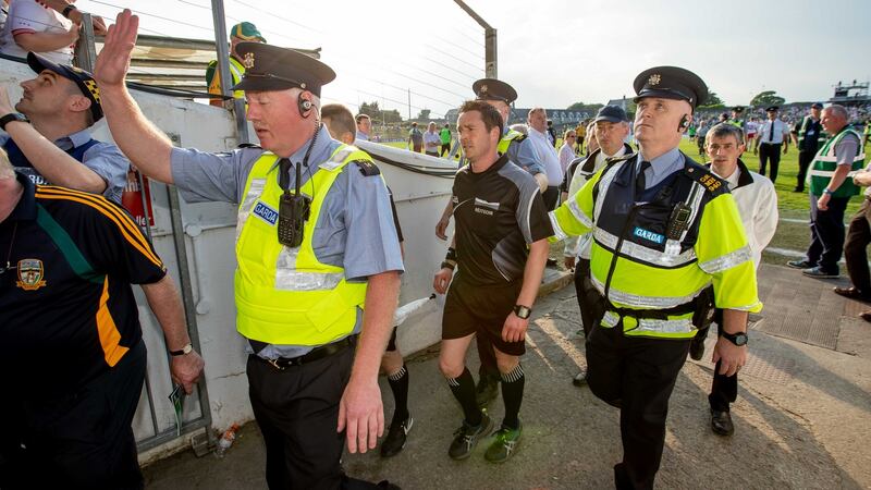 Referee Paddy Neilan is escorted off the field after the game. Photograph:  Morgan Treacy/Inpho