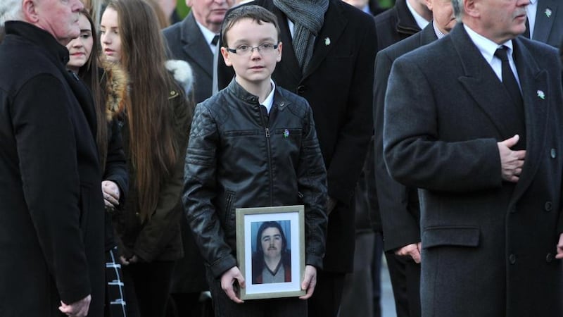 Brendan Megraw’s nephew Conal holds a photo of him at his funeral in Belfast yesterday. Photograph: Justin Kernoghan/Photopress Belfast