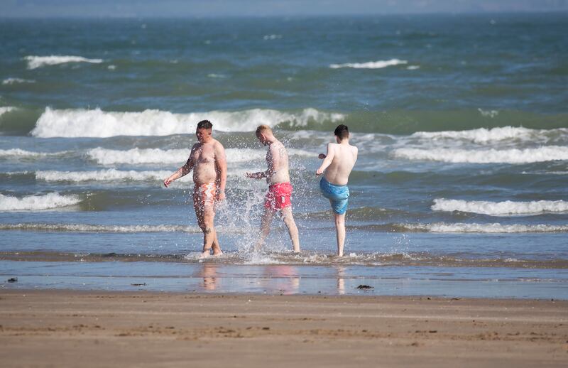 Three guys splash in the waters of Portmarnock Beach. Photograph: Colin Keegan/Collins