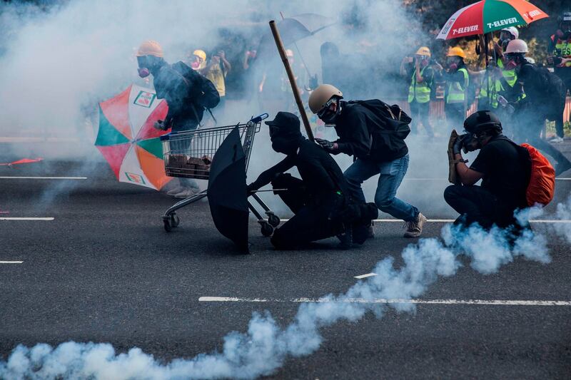 Protesters react among tear gas fired by police in the Sha Tin district of Hong Kong. Photograph:  Isaac Lawrence / AFP)
