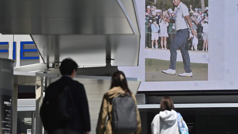 People walk in front of a screen showing the news of Japan’s Hideki Matsuyama winning the 85th Masters, at Akihabara district of Tokyo. Photograph: Getty Images
