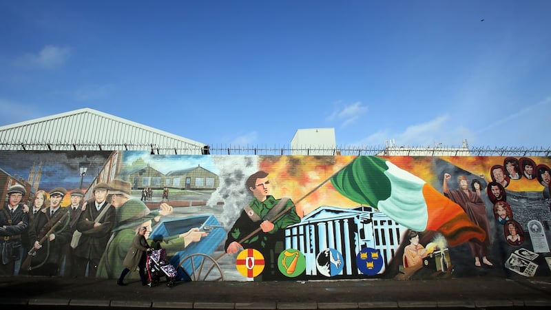 A woman with a pushchair walks past murals on Falls Road in 2017. Photograph: Paul Faith/AFP/Getty
